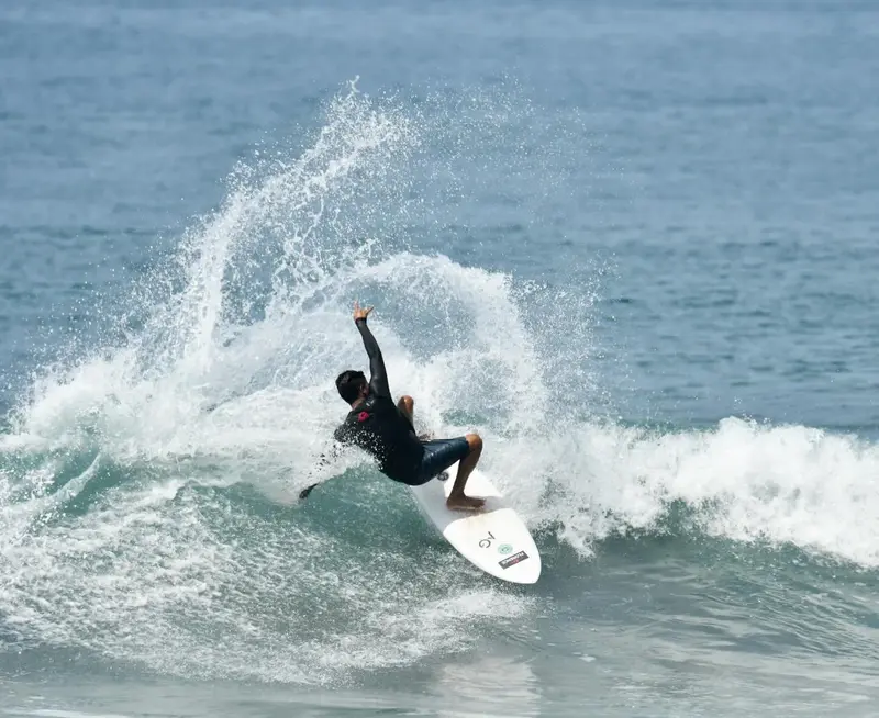 Surfer in a wetsuit executing a turn with spray flying around