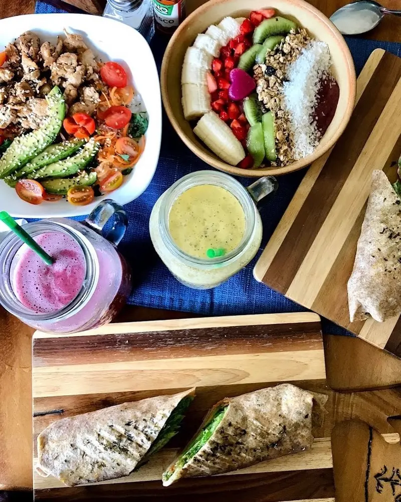 Bandeja con una ensalada, un bowl de açaí, tres smoothies en frascos y wraps