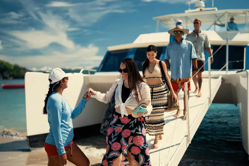 Pasajeros bajando por la rampa de un catamarán Costa Cat hacia la playa