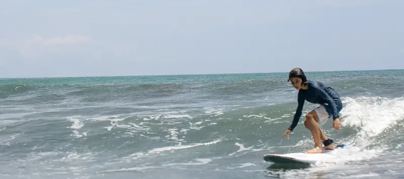 Surfista sobre una ola con espuma blanca y el mar abierto detrás