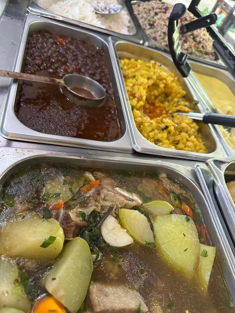 Bandejas del buffet con frijoles, arroz con maíz y una sopa de res con verduras