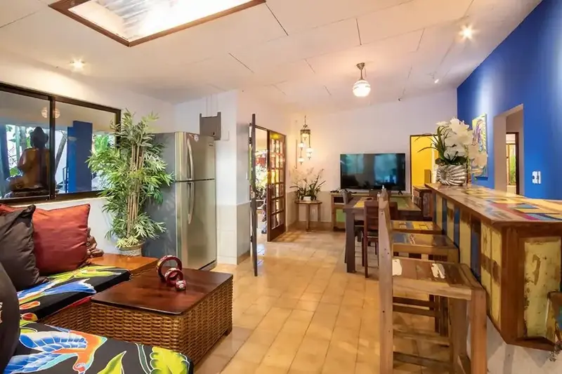 Sala común con sofás, televisor y una cocina con barra al fondo