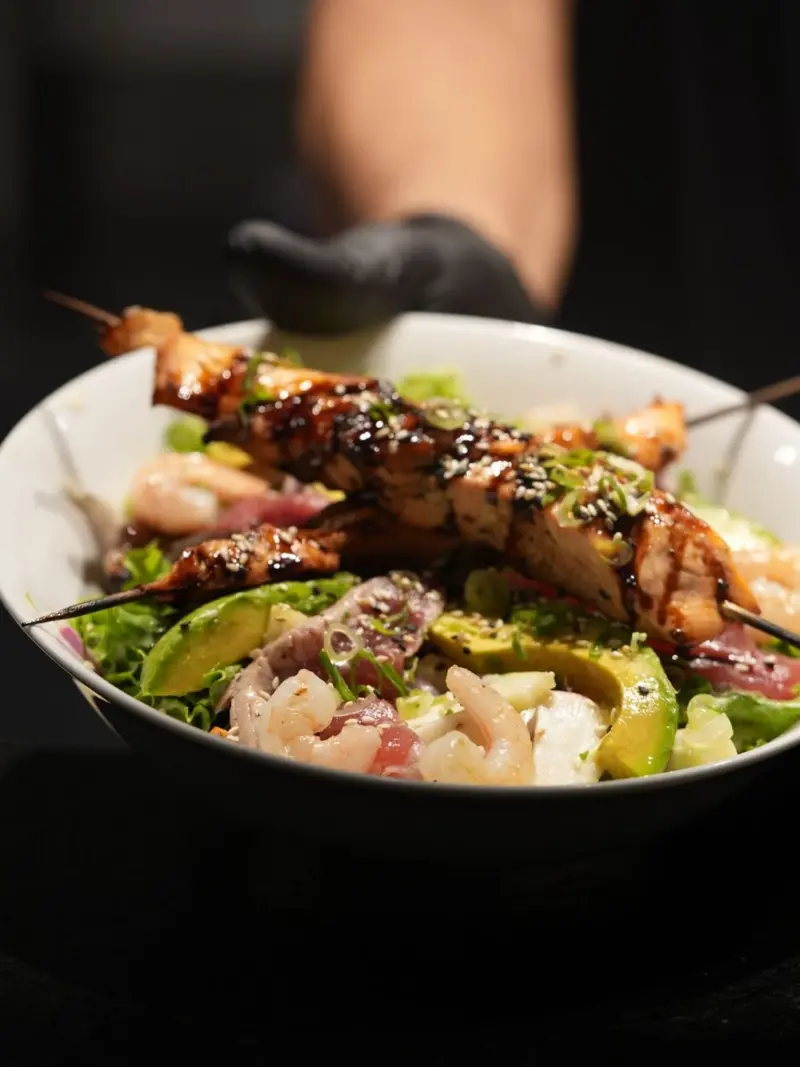 Reef Salad en un bowl blanco: brochetas a la parrilla, camarones y aguacate sobre vegetales