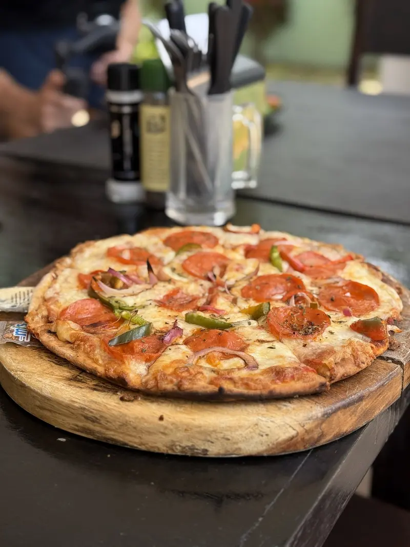 Pizza de pepperoni sobre una tabla de madera en una mesa oscura