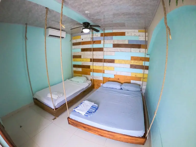 Habitación celeste con dos camas colgantes y ventilador de techo