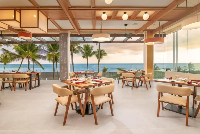 Terraza del sushi bar con mesas junto a ventanales con vista al mar
