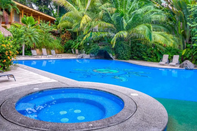 Piscina con jacuzzi circular y sillas, rodeada de plantas