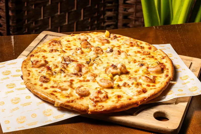 Pizza de masa delgada con camarones sobre una tabla de madera
