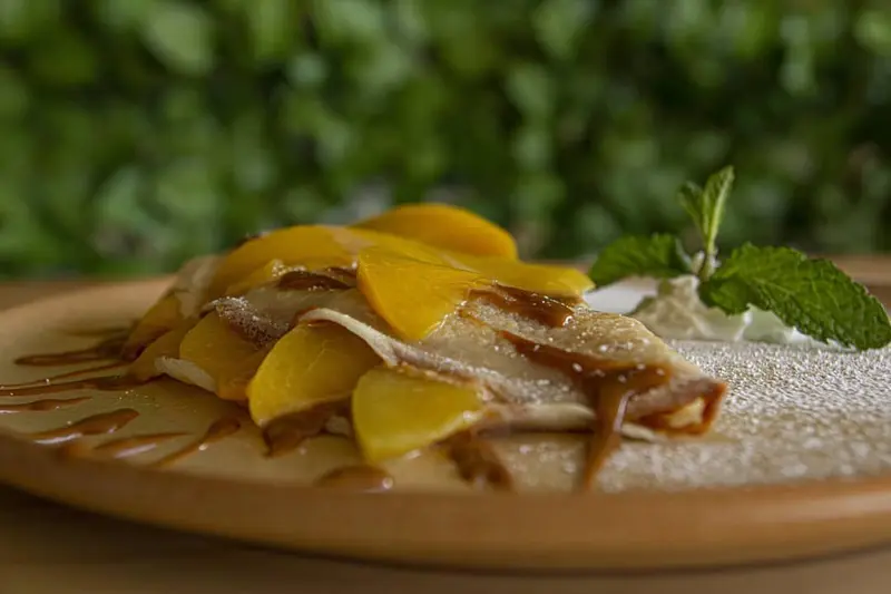 Crepe dulce con mango y crema sobre un plato de cerámica
