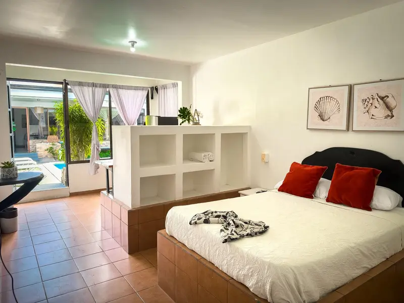 Habitación con cama matrimonial y puertas de vidrio que dan a la piscina