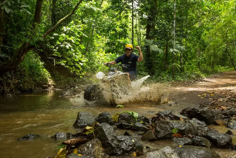Cuatrimoto levantando agua al cruzar una quebrada del bosque