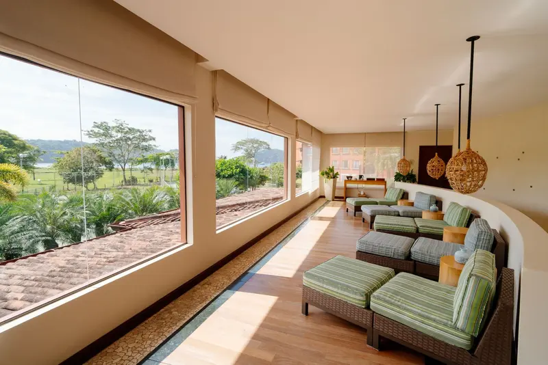 Sala de descanso con reposeras de mimbre frente a ventanales con vista a la bahía