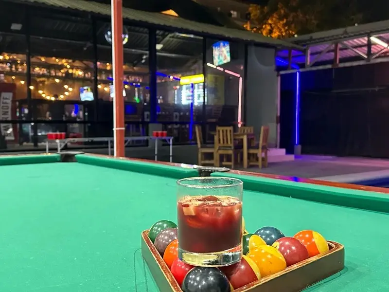 Mesa de billar con las bolas en el triángulo y un vaso de sangría encima
