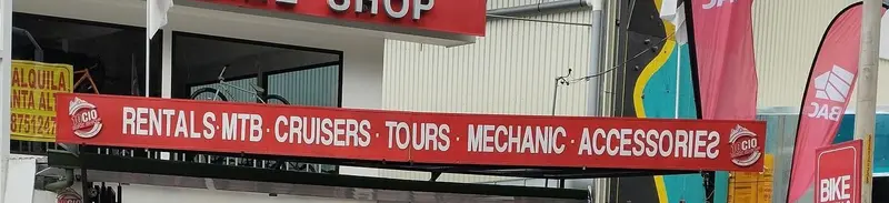 Cartel rojo «Rentals · MTB · Cruisers · Tours · Mechanic · Accessories» sobre la entrada de la tienda