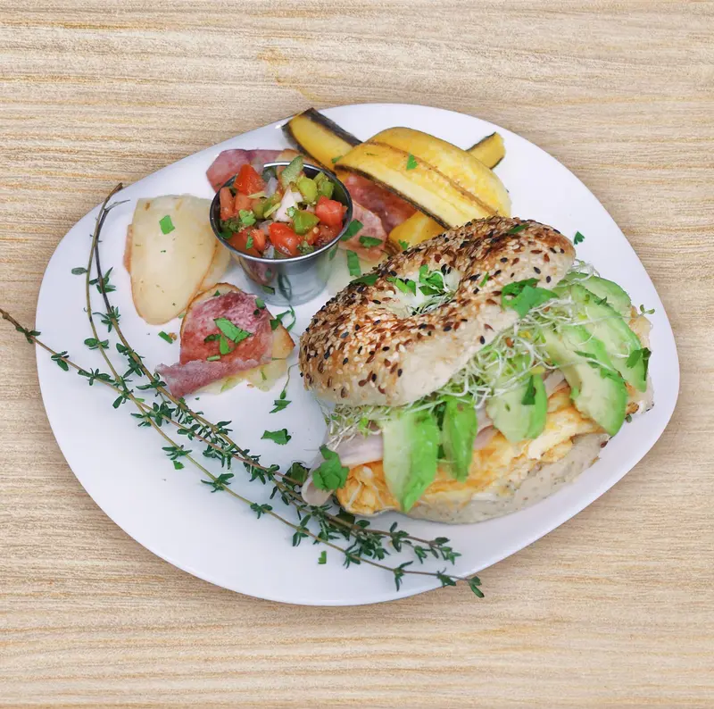 Bagel con huevo, aguacate y brotes, con pico de gallo y plátano maduro