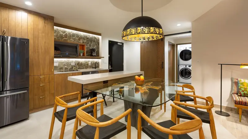 Cocina de una villa con isla de comedor, sillas de madera, refrigerador y lavadora