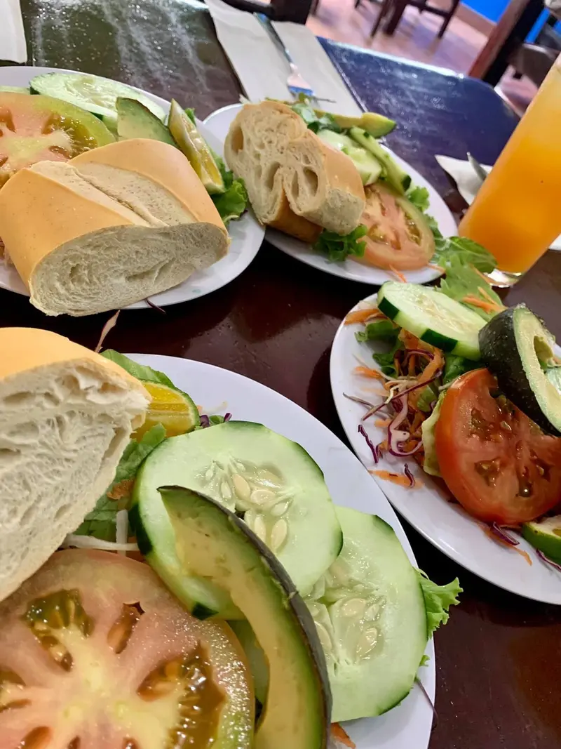 Platos de ensalada con aguacate, tomate y pepino con pan, sobre una mesa