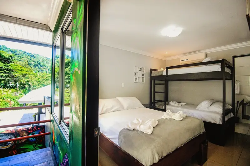 Habitación con camarote y cama doble junto a una ventana con vista al verde