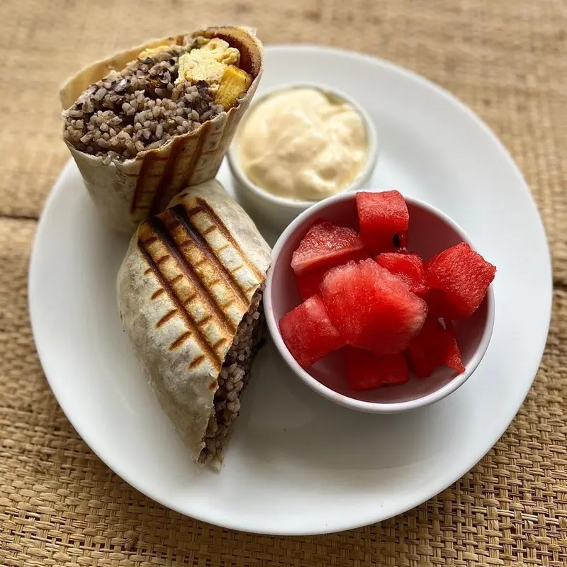 Burrito y sándwich a la plancha con crema y un bol de sandía en un plato blanco