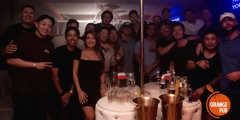 Grupo de amigos posando junto a una mesa VIP con botellas, vasos y hieleras doradas