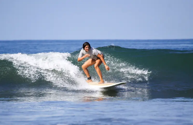 Surfista sobre una ola verde con la espuma rompiendo detrás