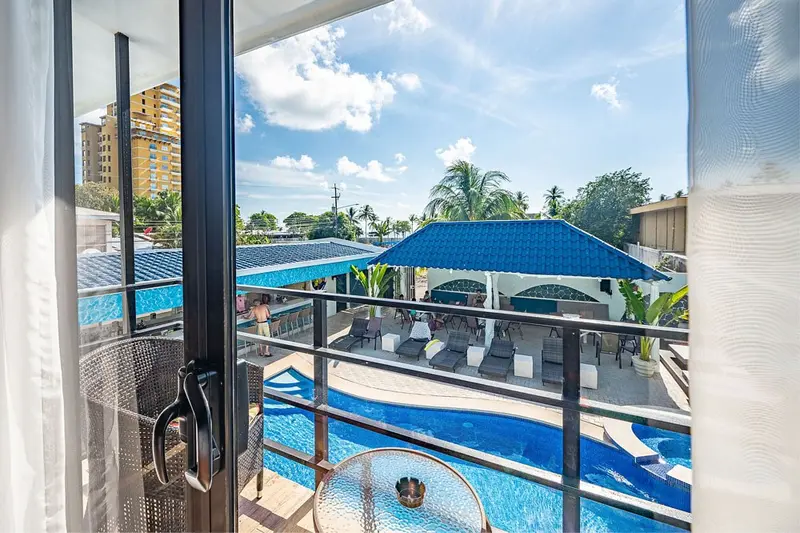 Vista desde un balcón del hotel hacia la piscina y las palmeras