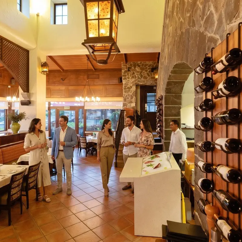 Interior del restaurante con pared de vinos y lámparas de hierro