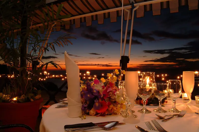 Mesa decorada con flores y servilletas en la terraza al atardecer