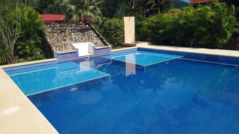 Piscina con una cascada pequeña de piedra y jardín alrededor