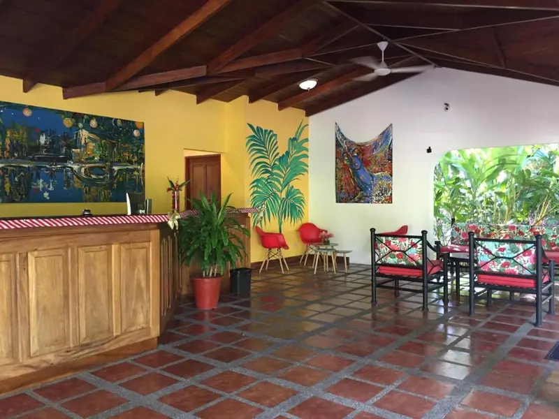 Recepción con mostrador de madera, piso de baldosa y sillas rojas
