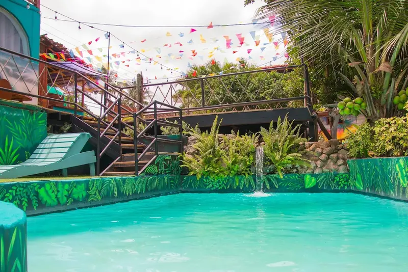 Piscina con cascada, escaleras y banderines de colores