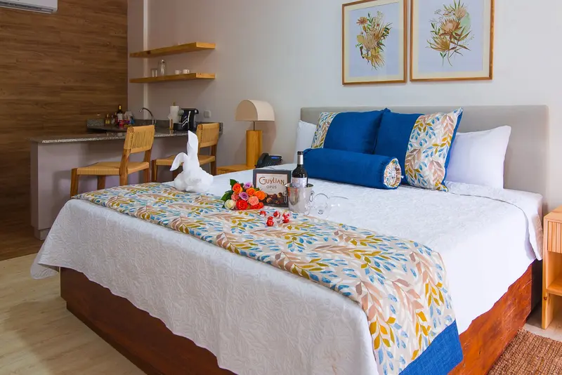 Habitación con cama king, colcha de flores y cuadros botánicos en la pared