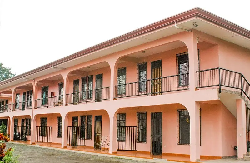 Edificio rosado de dos pisos con balcones y arcos, usado como apartamentos para estudiantes
