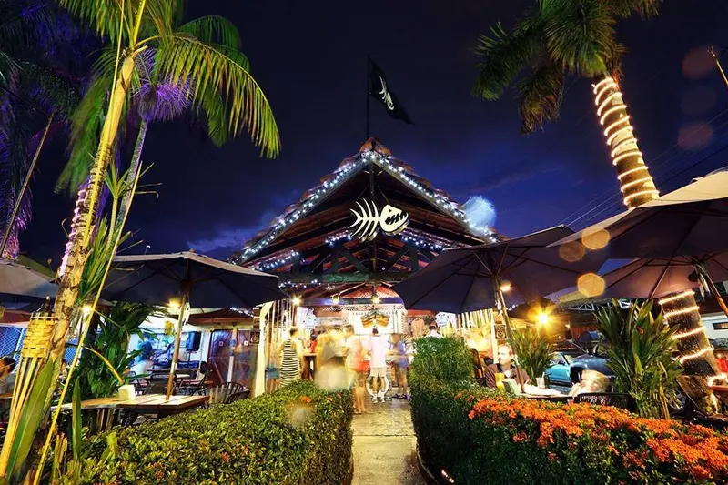 Terraza del restaurante de noche, con sombrillas encendidas, palmeras y luces en el techo