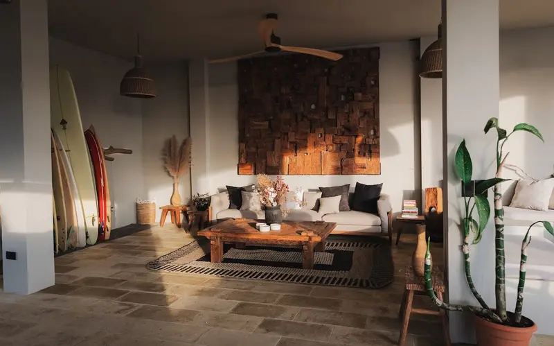 Sala con sofá, mesa baja de madera y tablas de surf apoyadas contra la pared