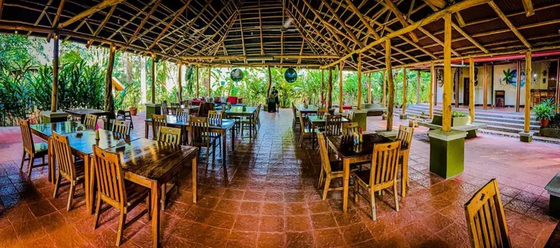 Restaurante al aire libre con techo de palma y mesas de madera