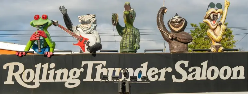 Rótulo Rolling Thunder Saloon sobre el techo, con figuras de animales tocando instrumentos