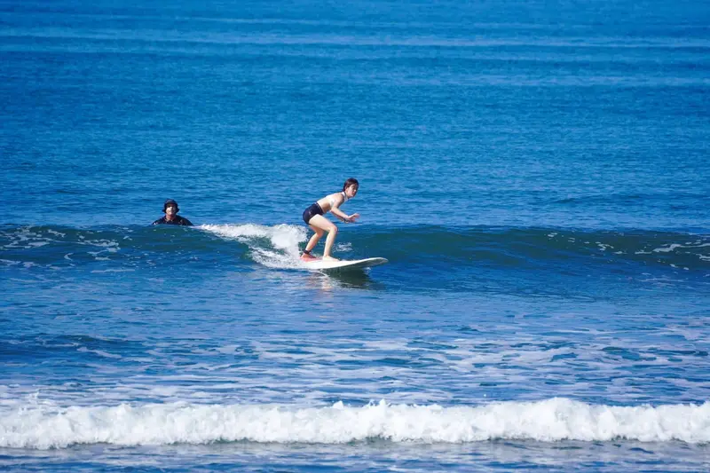 Alumna surfeando una ola frente a la costa