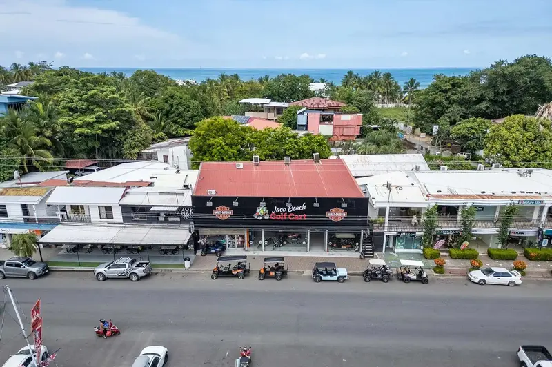 Fachada de la oficina de Jaco Beach Golf Cart con carritos y motos Harley-Davidson