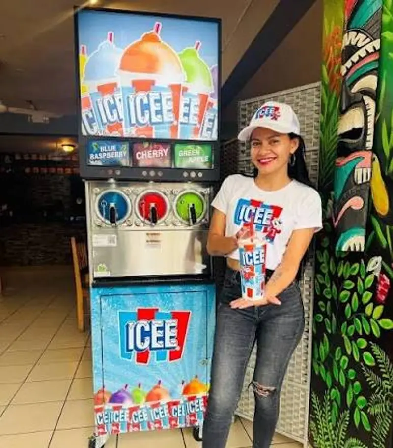 Máquina de ICEE con tres sabores y una empleada que sostiene un vaso