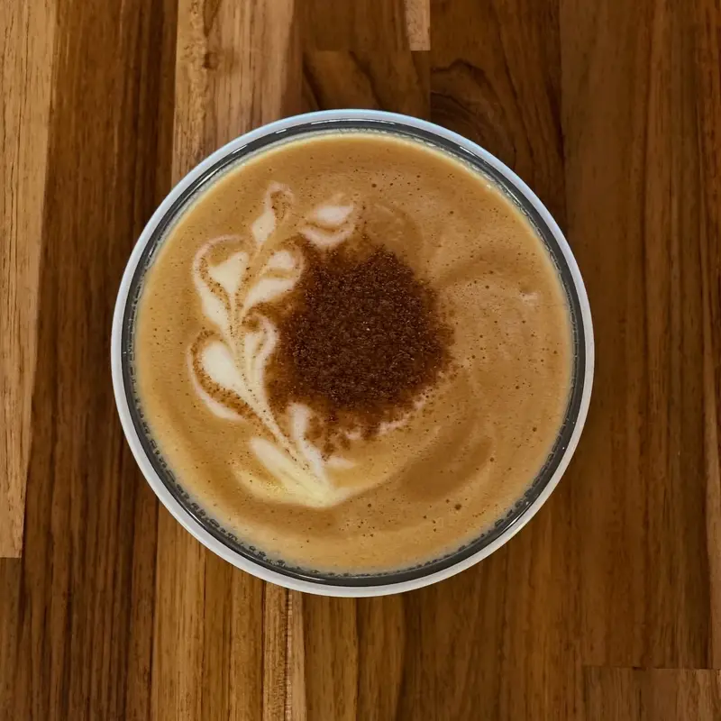 Capuchino con arte latte y canela sobre una mesa de madera, visto desde arriba