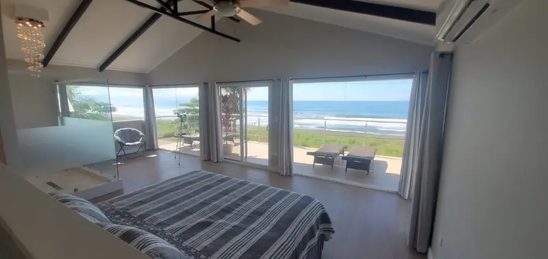 Dormitorio con cama grande y ventanales hacia la terraza y el mar