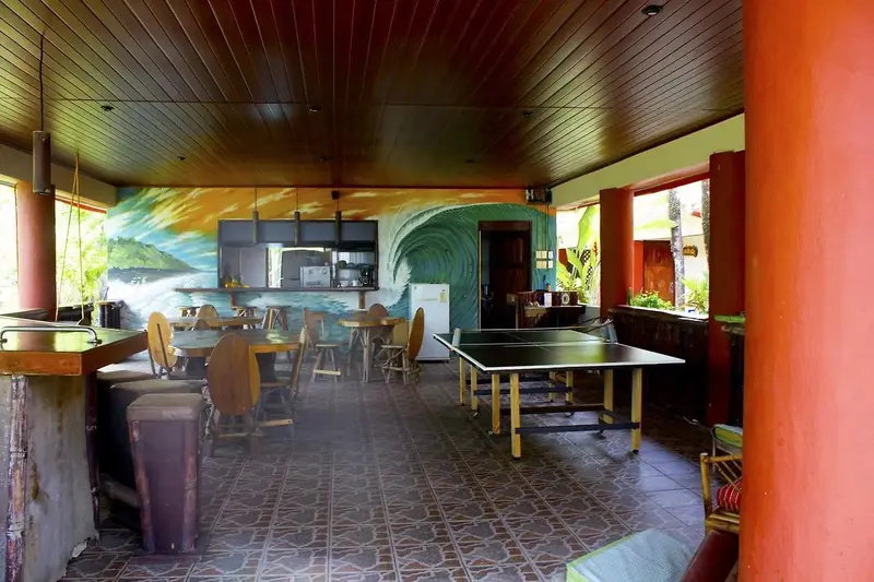 Área común techada con mesa de ping-pong, mesas y cocina al fondo