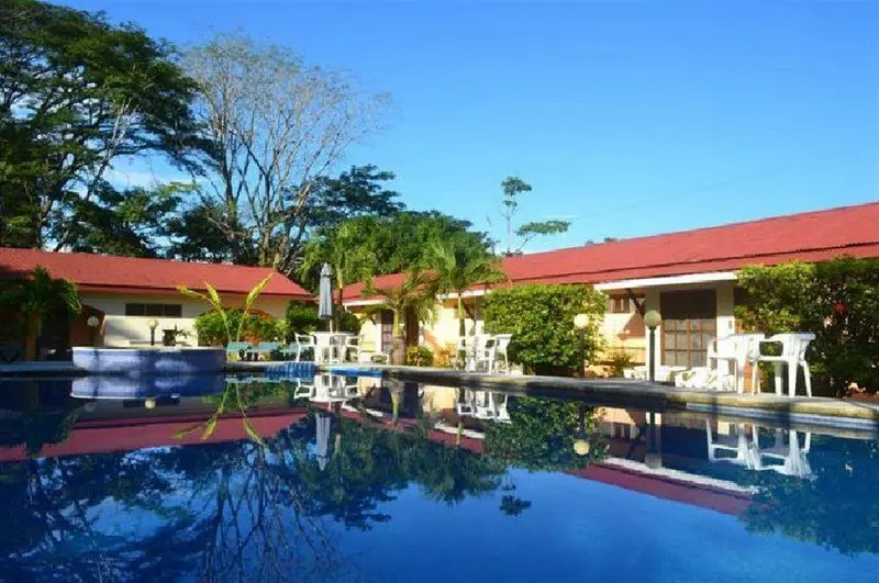 Piscina azul con escalones junto a edificios de techo rojo, reflejados en el agua