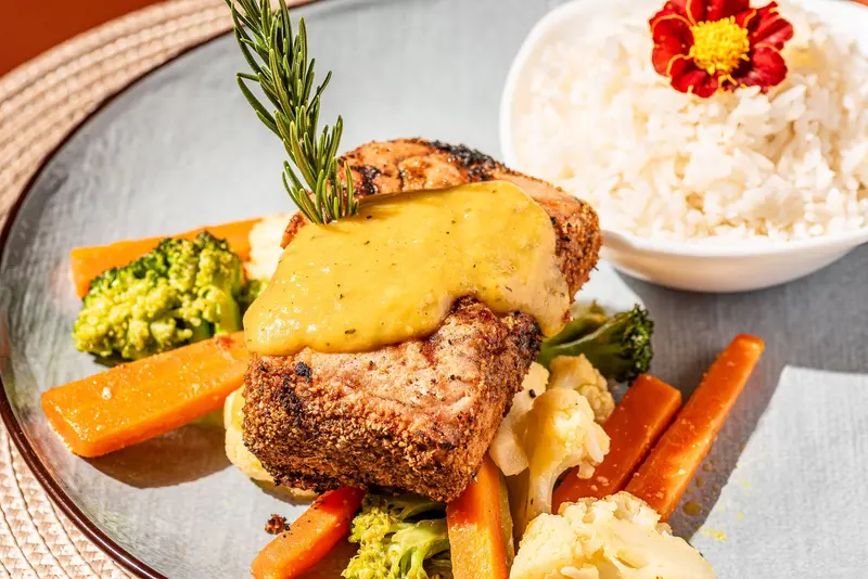 Filete de atún con costra y salsa de mango, con vegetales, arroz blanco y una flor