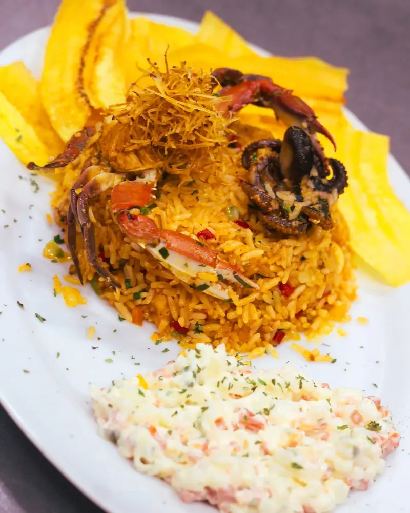 Arroz con mariscos con cangrejo y pulpo, chips de plátano y coleslaw