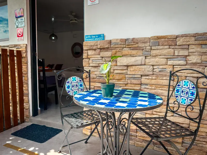 Mesa de mosaico azul con sillas de hierro frente a una pared de piedra