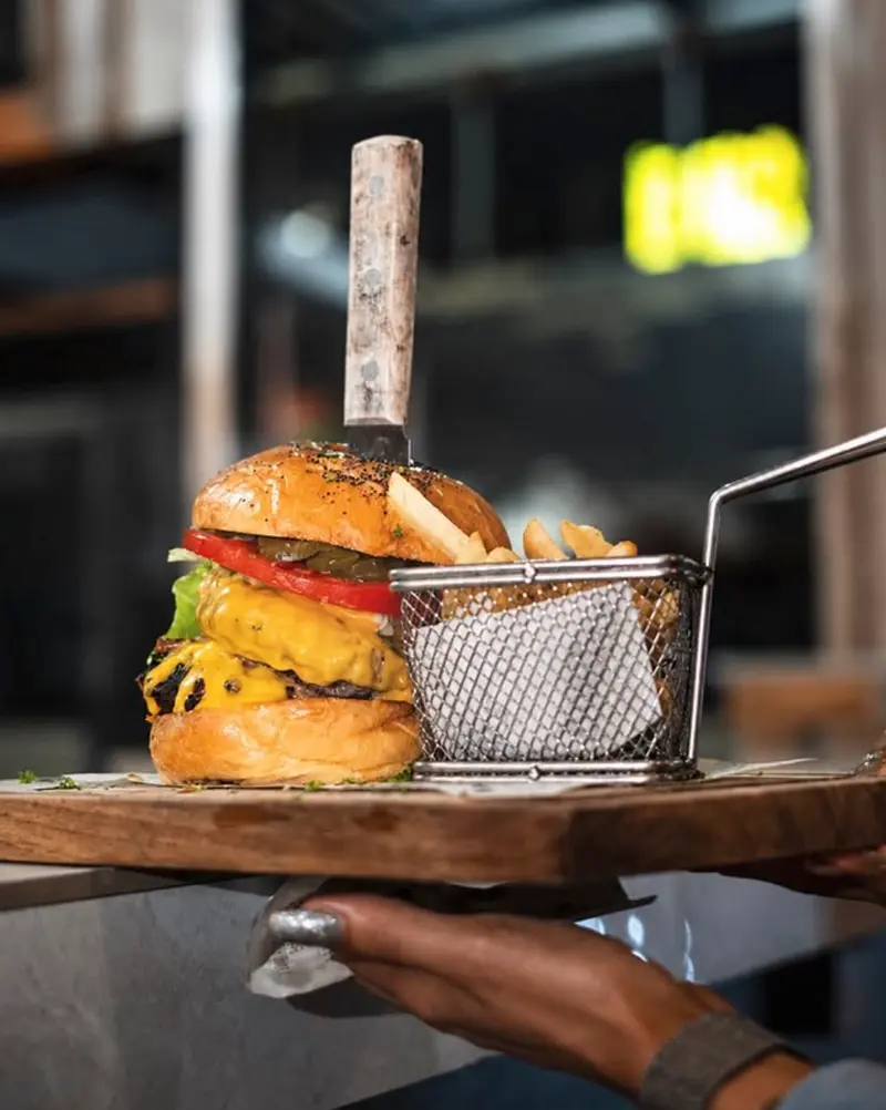 Hamburguesa con queso y papas fritas en canasta, servida en D'Corner