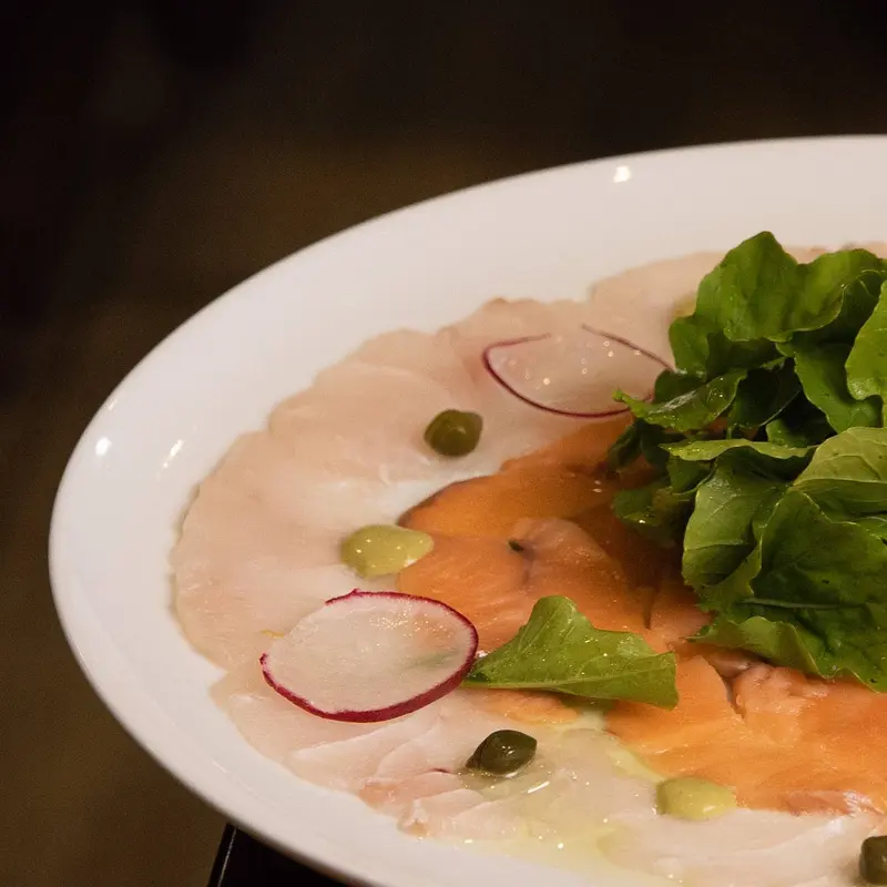 Carpaccio de pescado blanco y salmón con rúcula, alcaparras y rabanito