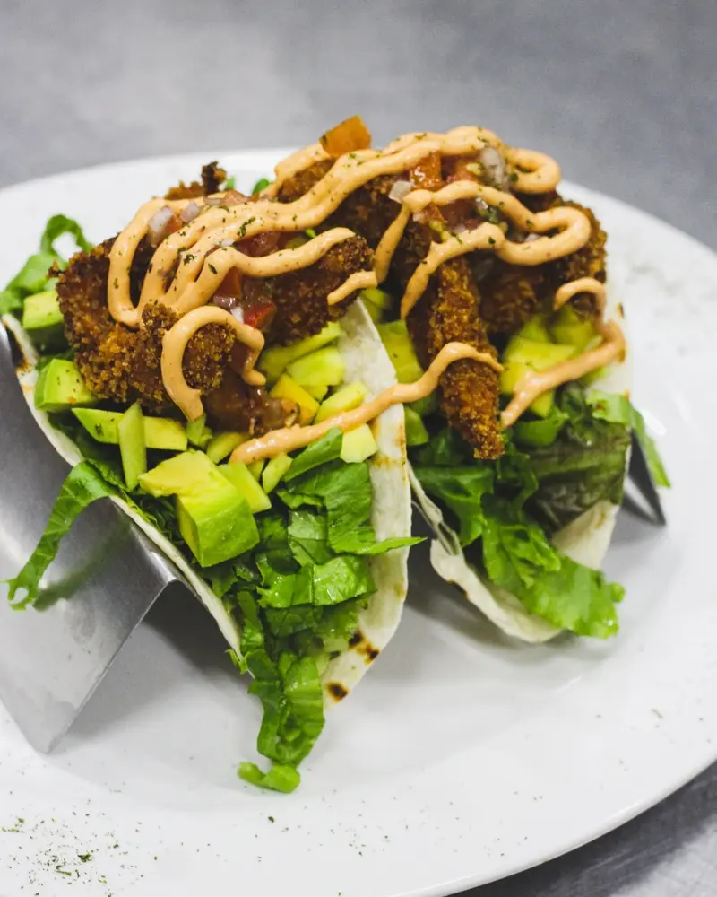 Tacos de pescado con aguacate y aderezo chipotle sobre hojas de lechuga